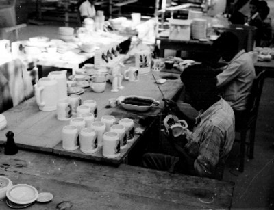 Artesanos pintando utensilios de alfareria en una fábrica de Tonalá